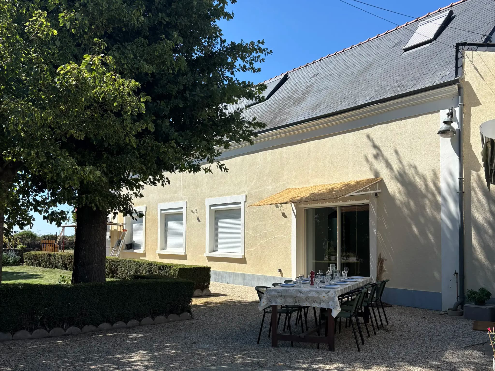 La maison de Lyly vue du jardin, avec la terrasse et la table dressée